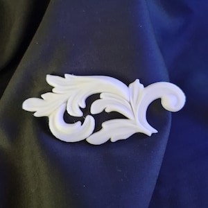 May include: White decorative trim with a floral design. The trim is made of a lightweight material and has a smooth finish.