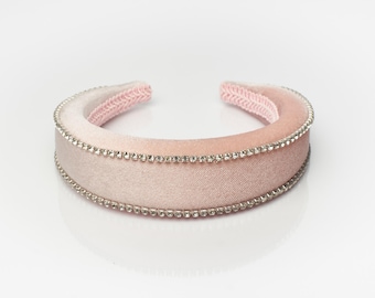 May include: A pink headband with a row of clear rhinestones around the edge.