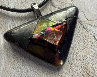 May include: A black triangle-shaped glass pendant with iridescent accents and a silver bail. The pendant is on a black cord.