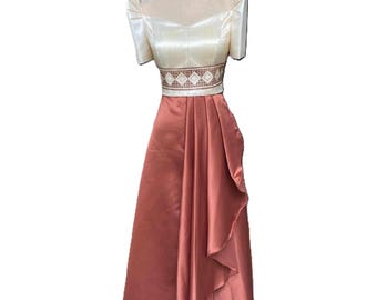 May include: A formal dress with a cream-coloured top and a rust-coloured skirt. The top has puffed sleeves and a decorative band at the waist. The skirt has a flowing design.