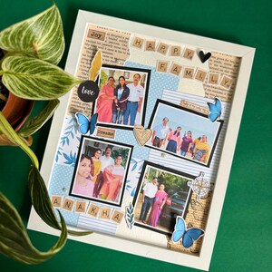 May include: A white picture frame with a collage of family photos. The photos are arranged in a grid pattern and are surrounded by decorative paper and embellishments. The words "Happy Family" are spelled out in letter tiles at the top of the frame. The words "Love", "Dreams", and "A.N.A.K.H.A." are also included in the collage.
