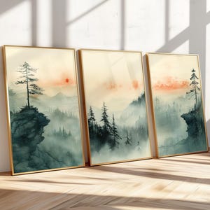 以下が含まれることがあります： 3つの額縁に入った水彩画は、最初の絵画では崖の上に1本の木、2番目の絵画では木々、3番目の絵画では崖の上に1本の木がある、霧のかかった森の風景を描いています。絵画は、青、緑、オレンジの色合いで、柔らかく落ち着いた色合いです。