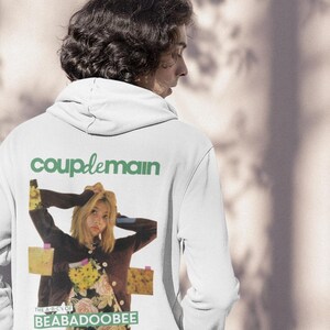 May include: White hoodie with a green "coup de main" logo and a graphic of a woman with the text "The A B C's of Beabadoobee" on the back.