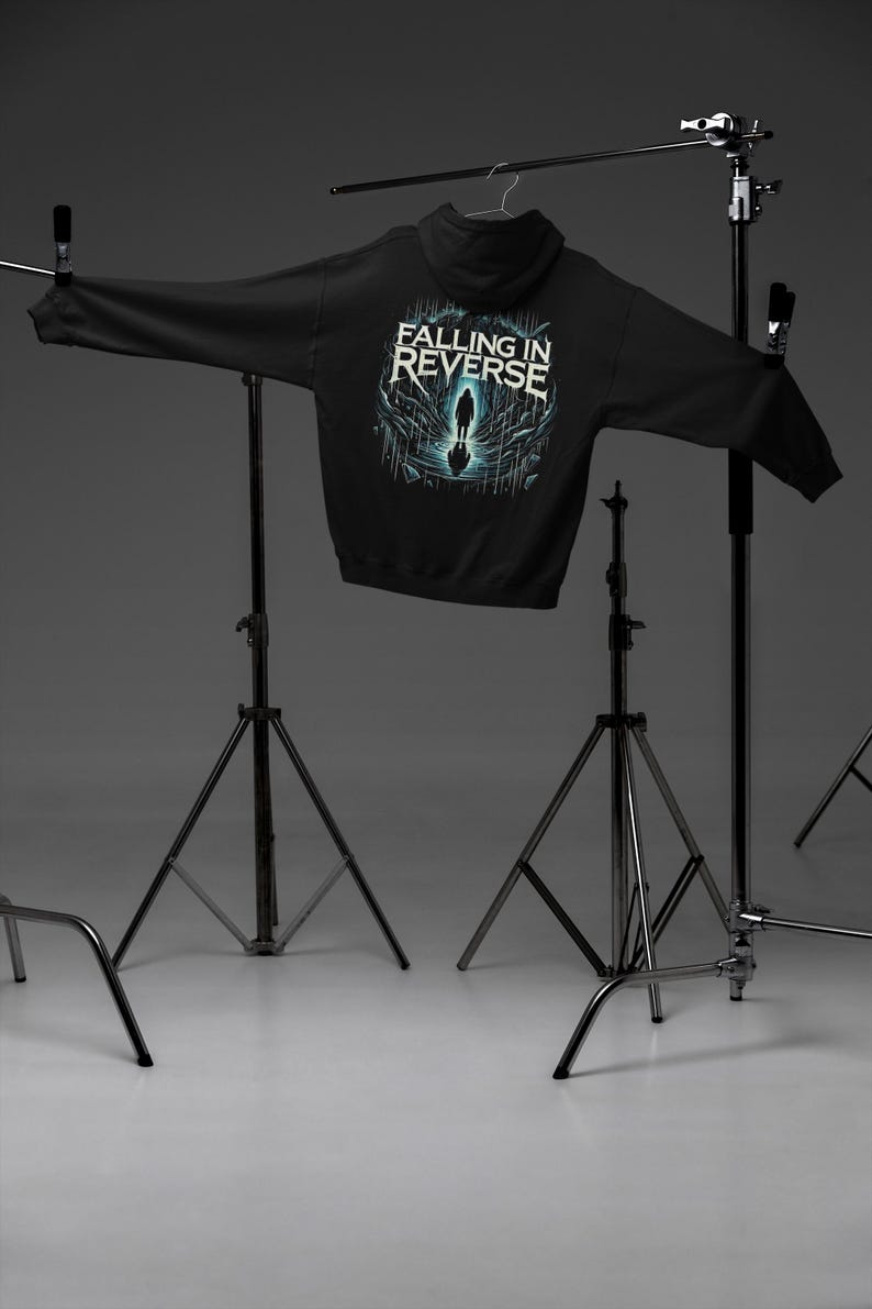 May include: Black hooded sweatshirt with a graphic print of a person walking on a cracked surface. The text "Falling in Reverse" is printed above the graphic.