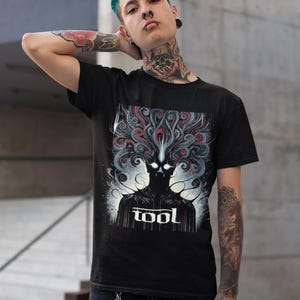 Puede incluir: Camiseta negra con un estampado gr&aacute;fico de una figura oscura con l&iacute;neas en espiral y la palabra "TOOL" en letras blancas.