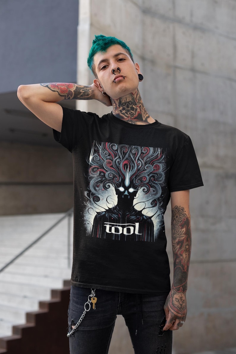 Puede incluir: Camiseta negra con un estampado gr&aacute;fico de una figura oscura con l&iacute;neas en espiral y la palabra "TOOL" en letras blancas.