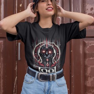May include: A black t-shirt with a graphic of a red and black face with the word "TOOL" printed below it.