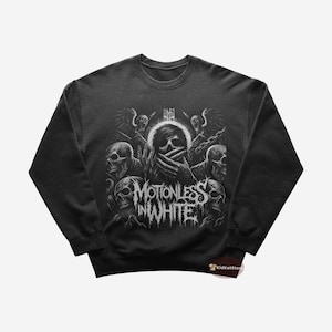 Może przedstawiać: Czarna bluza z nadrukiem graficznym przedstawiającym osobę z zakrytym twarzą rękami, otoczoną czaszkami i tekstem "Motionless In White".
