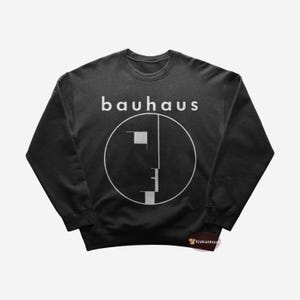 Puede incluir: Sudadera negra con un gráfico blanco de una cara en un círculo y la palabra "bauhaus" encima.