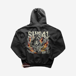 Può includere: Una felpa con cappuccio grigio scuro con una stampa grafica di uno scheletro che suona la chitarra in fiamme. Il testo "SUM 41" è stampato sul grafico e sotto il grafico.