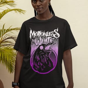 Może przedstawiać: Czarny T-shirt z fioletowym i białym nadrukiem przedstawiającym kruka i tekst "Motionless In White".