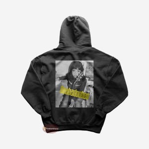 May include: Black hooded sweatshirt featuring a graphic print of a woman holding a microphone. The text "badoobles" is printed in yellow across the image.