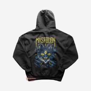 May include: Black hooded sweatshirt featuring a three-eyed cat graphic with the word "MASTODON" in yellow above the cat. The cat graphic is blue with yellow eyes and teeth. The sweatshirt has a drawstring hood.