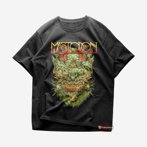 Puede incluir: Camiseta negra con un gráfico verde y rojo de un monstruo con la palabra "MASTODON" en letras doradas arriba.