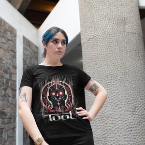 May include: A black t-shirt with a graphic print of a red and black robot head with the word "TOOL" printed below it.