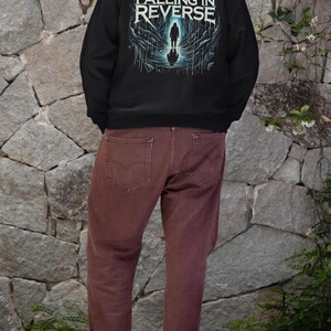 May include: Black hooded sweatshirt with a graphic print of a person standing in a dark, watery environment. The text "Falling in Reverse" is printed in white on the front of the sweatshirt.