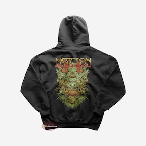 Puede incluir: Sudadera con capucha negra con un gráfico verde y dorado de un monstruo con la palabra "Mastodon" encima.
