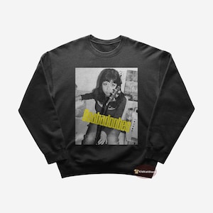 May include: Black sweatshirt featuring a graphic print of a woman holding a guitar. The text "Bebadoobee" is printed in yellow on the graphic.