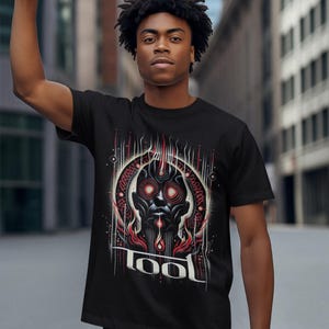 May include: A black t-shirt with a graphic print of a stylized face with red eyes and flames. The text "TOOL" is printed below the graphic.