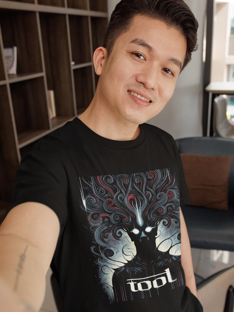 Puede incluir: Una camiseta negra con un estampado gr&aacute;fico de una figura oscura con el pelo en espiral y la palabra "TOOL" en letras blancas.