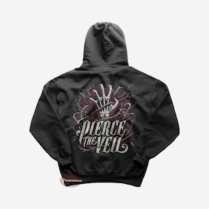 Peut inclure: Un sweat à capuche gris foncé avec un imprimé graphique d'une main squelettique qui sort d'un réseau de vignes. Le texte "PIERCE THE VEIL" est imprimé en lettres blanches et grises sous la main.