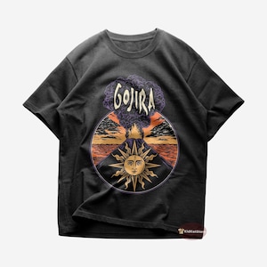 Op de afbeelding: Zwart T-shirt met een afbeelding van een vulkaan die uitbarst met een zon en het woord "GOJIRA" erboven.