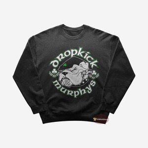 Peut inclure: Sweat-shirt noir avec un graphique blanc d'un bouledogue portant un chapeau et un cigare. Le graphique dit "Dropkick Murphys" avec des trèfles autour.