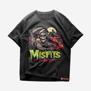 May include: Black t-shirt featuring a graphic of a grim reaper holding a scythe and a skull-shaped ice cream cone, with a red devil and a haunted house in the background. The word "MISFITS" is displayed in green and yellow.