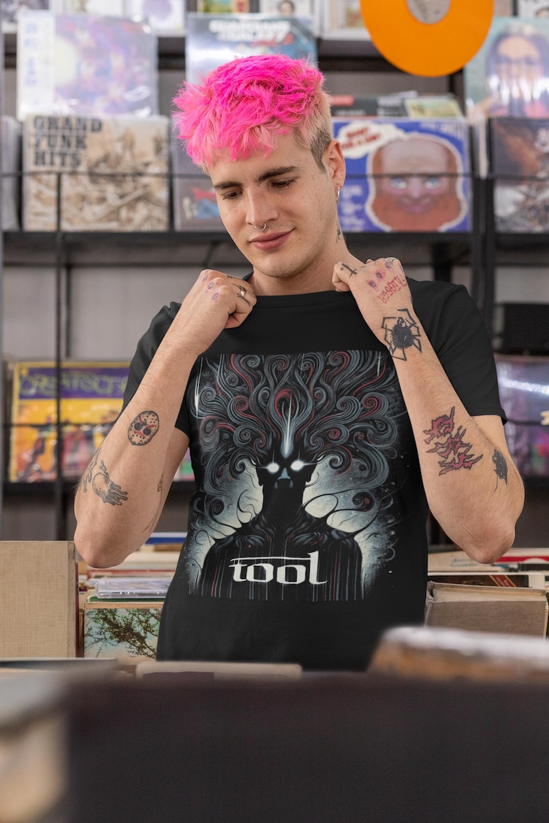 Puede incluir: Una camiseta negra con un estampado gr&aacute;fico de una figura oscura con l&iacute;neas en espiral y la palabra "TOOL" en letras blancas.