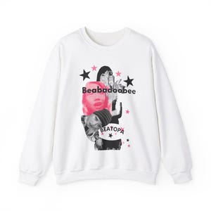 May include: White sweatshirt featuring a graphic print of a woman's face with the text "Beabadoobee" and "Beatopia" in black and pink.