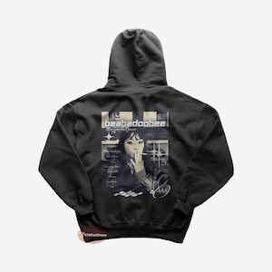 May include: Black hooded sweatshirt featuring a graphic print of a woman holding a cigarette. The graphic also includes the text "beabadoobee" and "the perfect pair".