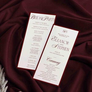 May include: Two wedding programs with burgundy borders and text on a burgundy satin background. One program lists the bridal party, and the other welcomes guests to Eleanor and Stephen's wedding. The ceremony details are also listed.