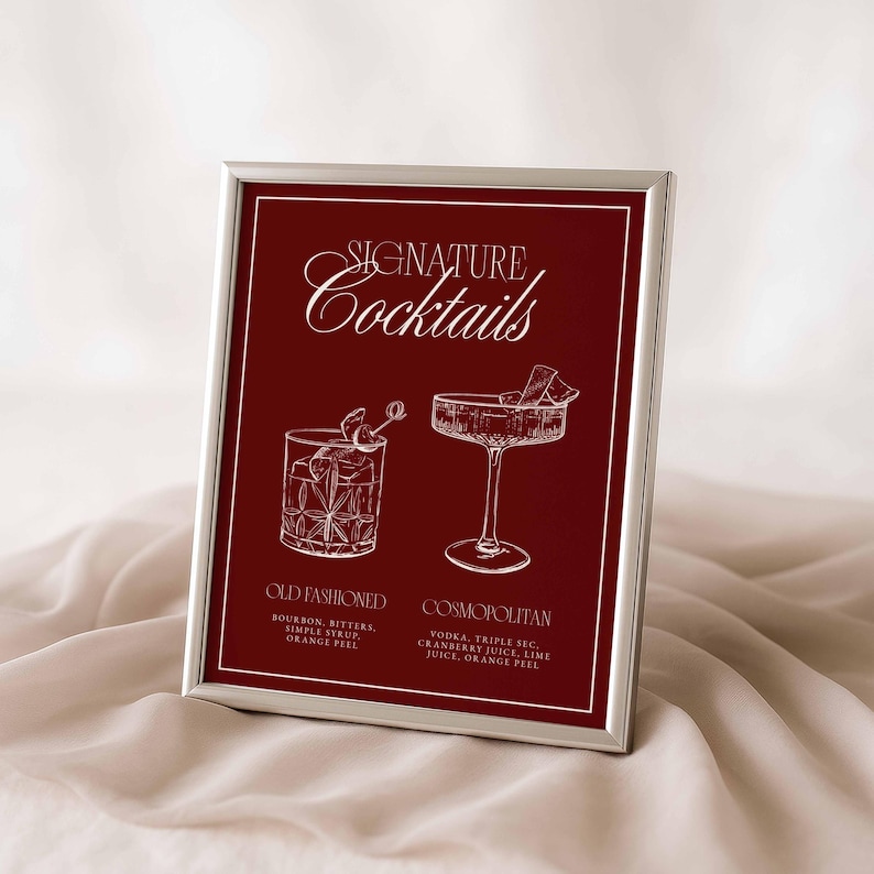 Puede incluir: Impresi&oacute;n enmarcada con fondo burdeos, texto blanco e ilustraciones. El texto dice "Signature Cocktails" encima de dos ilustraciones de c&oacute;cteles. Debajo, los nombres "Old Fashioned" y "Cosmopolitan" con sus ingredientes.
