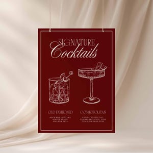 Puede incluir: Un p&oacute;ster burdeos con la inscripci&oacute;n "SIGNATURE Cocktails" en escritura cursiva. Presenta dibujos lineales de un Old Fashioned y un Cosmopolitan, con sus ingredientes. El p&oacute;ster est&aacute; suspendido por dos cuerdas.