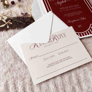 May include: A wedding invitation suite featuring a burgundy and white design. The invitation card includes the event details, while the RSVP card has fields for the guest's name, acceptance, or regrets, and dietary restrictions. The suite is accompanied by a white envelope.