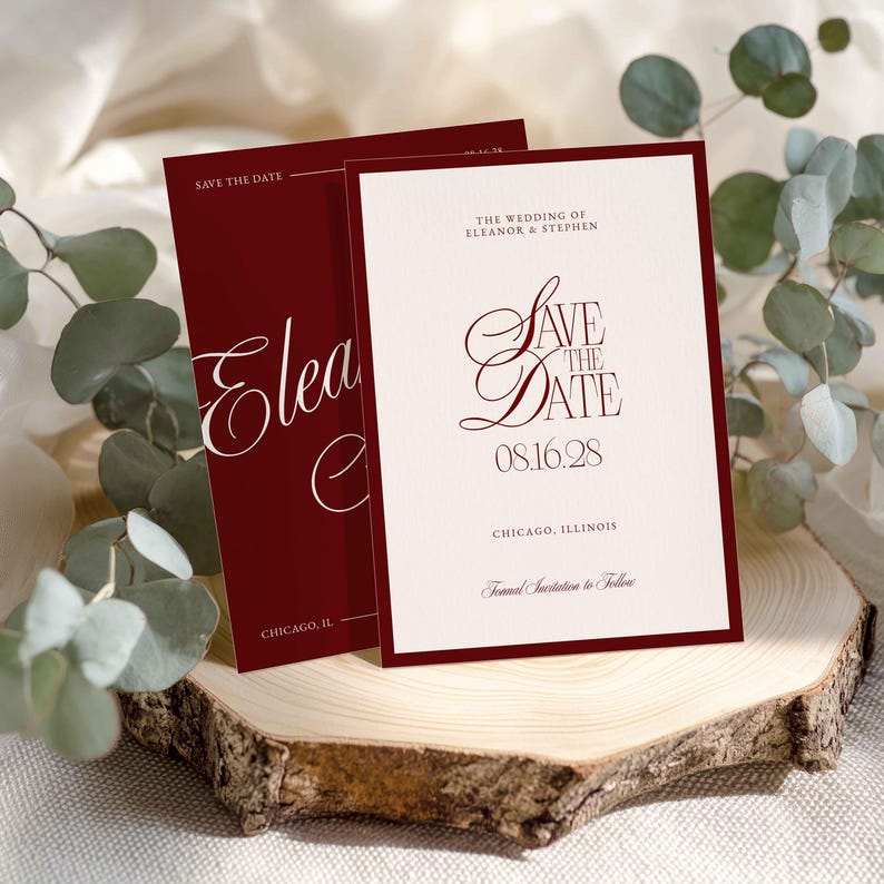 Op de afbeelding: Bordeauxrode en cr&egrave;mekleurige trouwkaarten "Save the Date". De kaarten hebben een elegant lettertype met de namen Eleanor & Stephen, de datum 08.16.28 en de locatie Chicago, Illinois. De kaarten worden gepresenteerd op een houten schijf.