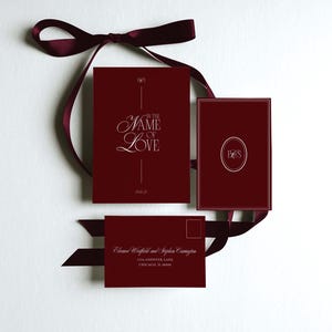 May include: Burgundy wedding invitation suite with a ribbon. The suite includes a card with "In the Name of Love" in elegant script, a card with initials, and an envelope with names and address. The date is 09.16.25.