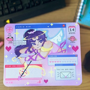 May include: A rectangular mousepad with a pixelated illustration of Cupid. The design features a purple-haired character with angel wings, surrounded by computer-themed graphics, hearts, and the text "Cupid.exe". The color palette includes pink, blue, and yellow.