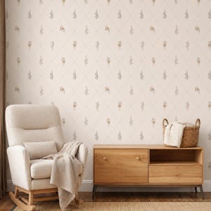Può includere: Un muro color crema con un motivo a rombi e accenti floreali. A sinistra, una poltrona a dondolo beige con una coperta e un cuscino abbinati. A destra, un mobile in legno con un cesto intrecciato e una coperta.