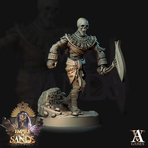 Può includere: Una dettagliata figura scheletrica grigia di una mummia che tiene in mano una lama curva. La figura è avvolta in bende e si trova su una piccola base rocciosa. La figura fa parte della collezione "Empire of Sands".