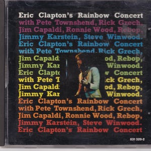 Op de afbeelding: Een zwarte en gele cassettebanddoos met de tekst "Eric Clapton's Rainbow Concert" en een lijst met muzikanten, waaronder Pete Townshend, Rick Grech, Jim Capaldi, Ronnie Wood, Rebop, Jimmy Karstein en Steve Winwood.