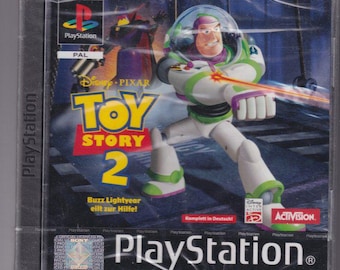 May include: A PlayStation game case for Toy Story 2 featuring Buzz Lightyear in a green and white spacesuit holding a laser gun. The game is rated PAL and is published by Activision.
