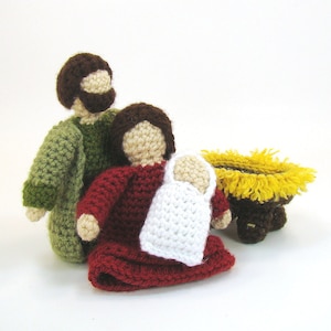 May include: Crocheted nativity scene featuring a green and brown Joseph, a red and brown Mary, a white baby Jesus, and a yellow manger.
