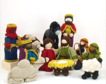 May include: A nativity scene set with crocheted figures, including a camel, donkey, sheep, and several people. The figures are all dressed in traditional clothing and are arranged in a circle around a manger.