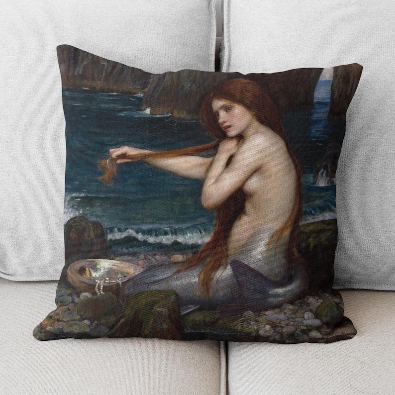 Puede incluir: Una pintura de una sirena con el pelo largo y rojo sentada en una roca junto al mar. Est&aacute; sujetando un mech&oacute;n de su pelo en la mano y mirando hacia el agua. La pintura est&aacute; realizada en un estilo realista y los colores son apagados.