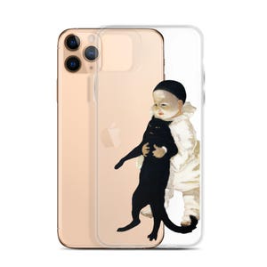 以下が含まれることがあります： 透明な携帯電話ケースに金色の携帯電話が入っています。ケースには、白い服を着た子供が黒い猫を抱いている絵が描かれています。子供は黒い帽子をかぶり、真剣な表情をしています。
