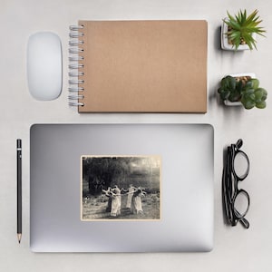 May include: A sticker featuring a sepia-toned image of five figures in flowing dresses holding a long pole, dancing in a circle. The background shows a field and trees. The sticker is on a laptop.