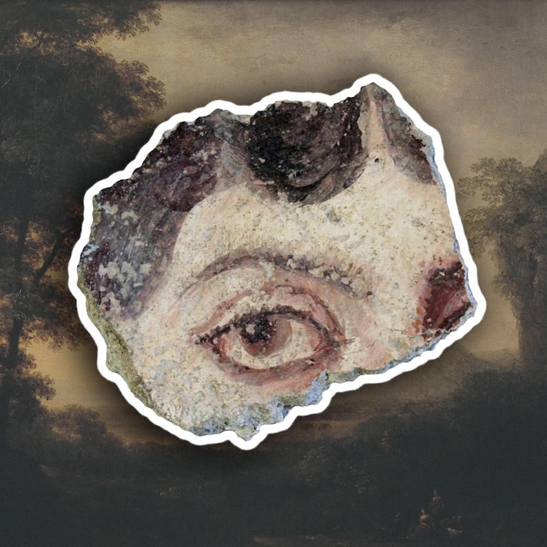 May include: Fragment of a painted artwork featuring a detailed eye. The eye is rendered in shades of brown, red, and beige, with dark hair above. The artwork is on a textured, irregular surface, possibly stone or plaster.