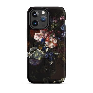 Puede incluir: Una funda de tel&eacute;fono negra con un dise&ntilde;o floral. La funda presenta un ramo de flores rosas, blancas y azules en un jarr&oacute;n oscuro. La funda del tel&eacute;fono tiene un recorte para el objetivo de la c&aacute;mara.