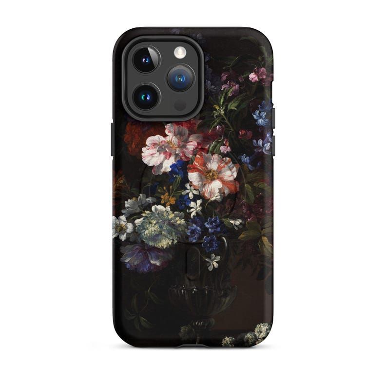 Puede incluir: Una funda de tel&eacute;fono negra con un dise&ntilde;o floral. La funda presenta un ramo de flores rosas, blancas y azules en un jarr&oacute;n oscuro. La funda del tel&eacute;fono tiene un recorte para el objetivo de la c&aacute;mara.